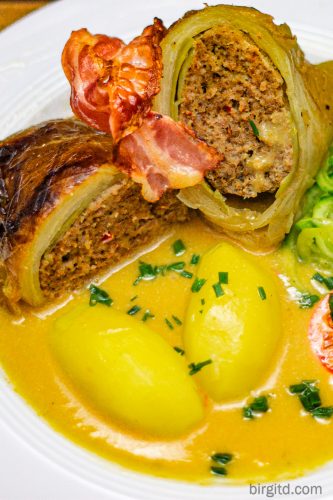 Kohlroulade aufgeschnitten auf einem Teller mit Sauce und Kartoffeln angerichtet